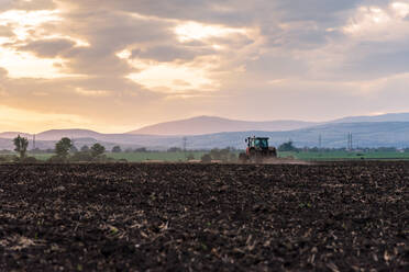 Traktor pflügt Felder bei Sonnenuntergang. - CAVF80529