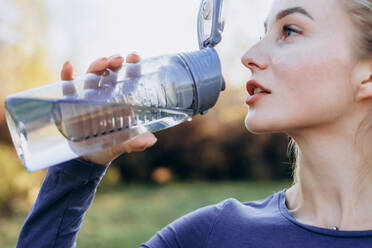 Fitness im Park, Mädchen trinkt Wasser aus einer Flasche, Nahaufnahme. - CAVF80538