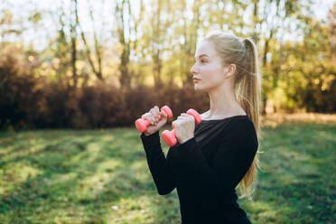 Profil eines schlanken Mädchens mit Hanteln im Freien, Fitness im Park. - CAVF80550