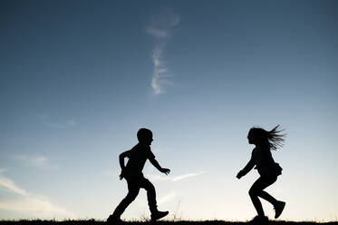 Silhouettierte Kinder, die zusammen in Waco Texas laufen - CAVF80568