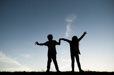 Silhouetted Kids Playing on Hill in Waco Texas - CAVF80570