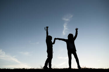 Silhouetted Kids Playing on Hill in Waco Texas - CAVF80572