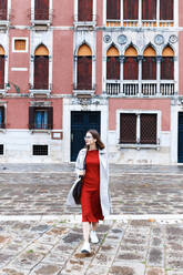 Junge Touristin in Kleid und Mantel in den Straßen von Venedig - CAVF80588