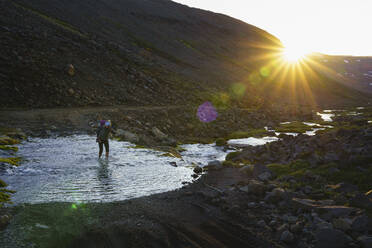 Famale Backpacker Crossing Glacial River In Iceland Highlands - CAVF80639