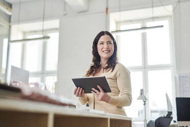 Smiling female executive using digital tablet at office - MMIF00218