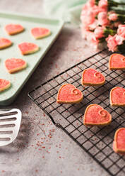 Close up of Valentine's day heart cookies cooling on a pan and rack. - CAVF80689