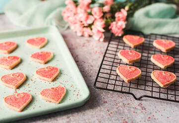 Nahaufnahme von Herzkeksen zum Valentinstag, die auf einer Pfanne und einem Rost abkühlen. - CAVF80690