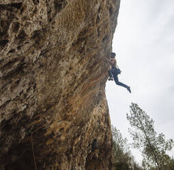 Hemdsärmeliger Kletterer, der eine Sportkletterroute an einem spanischen Felsen klettert. - CAVF80814