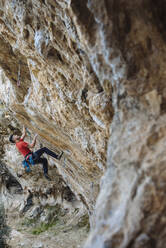 Climber begining a hard sport climbing route in a cave. - CAVF80817