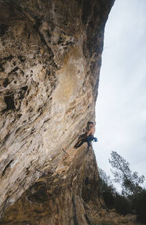 Hemdsärmeliger Kletterer, der eine Sportkletterroute an einem spanischen Felsen klettert. - CAVF80819