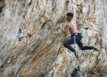 Shirtless climber sending a sport climbing route on spanish crag. - CAVF80820