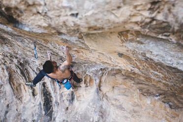 Shirtless climber sending a sport climbing route on spanish crag. - CAVF80821