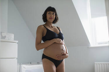 Schöne schwangere Frau in BH und Höschen hält Bauch - HOXF06224