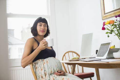 Porträt selbstbewusste schwangere Frau trinkt Tee am Laptop - HOXF06233
