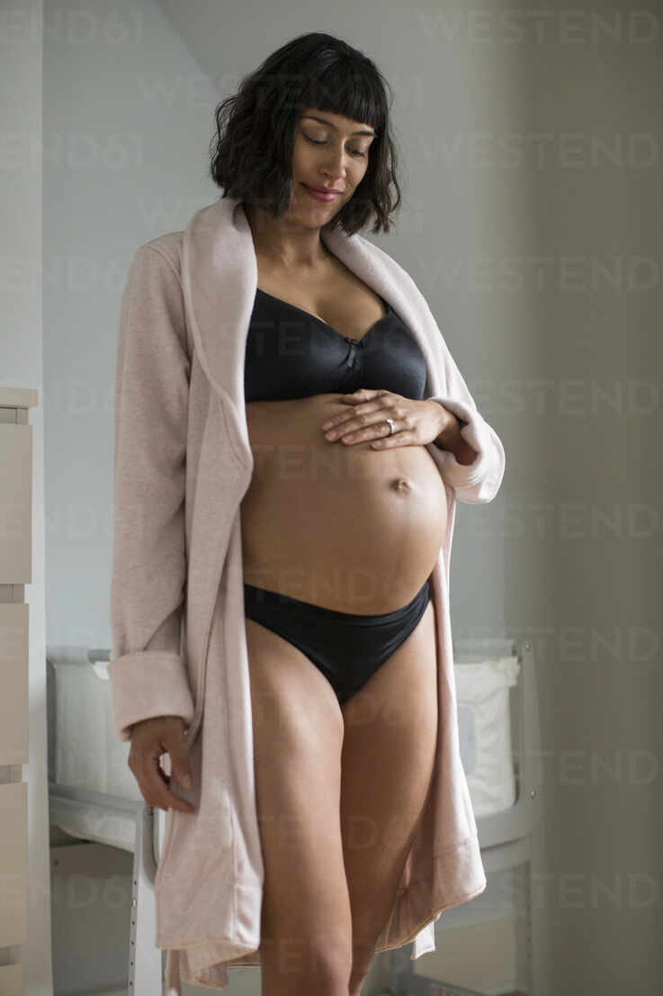 Pregnant woman in bra and panties touching stomach stock photo