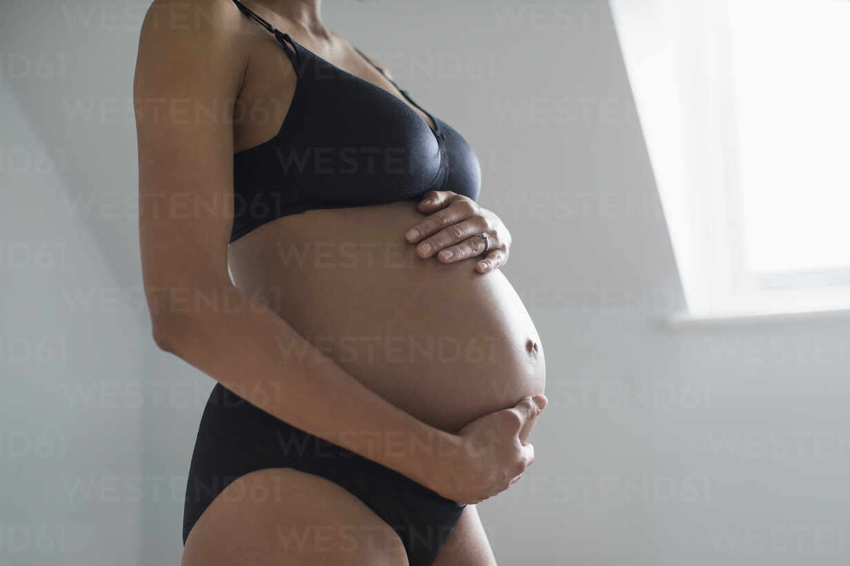 Pregnant woman in bra and panties touching stomach - Stock Image -  F030/0575 - Science Photo Library