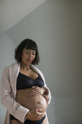 Schwangere Frau im BH hält Bauch - HOXF06257