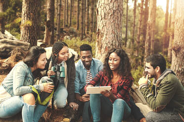 Young friends using digital tablet in woods - CAIF26310