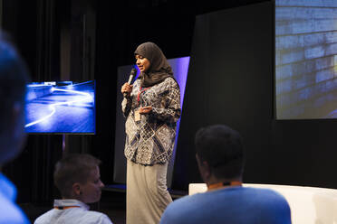 Weibliche Rednerin im Hidschab auf der Bühne spricht zum Publikum - CAIF26339