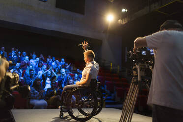 Rednerin im Rollstuhl auf der Bühne winkt dem Publikum zu - CAIF26363