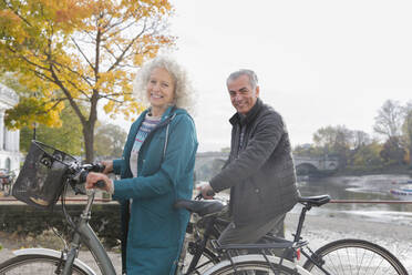 Porträt lächelnd Senior Paar Radfahren entlang Herbst Fluss - CAIF26384