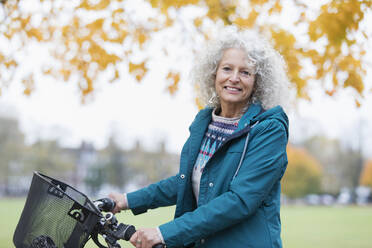 Porträt zuversichtlich, lächelnd ältere Frau Fahrradfahren im Herbst Park - CAIF26408