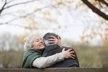 Zärtliches, zartes älteres Paar, das sich im Herbst im Park umarmt - CAIF26412