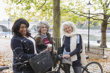 Porträt lächelnd, zuversichtlich, aktive ältere Frauen Freunde mit Kaffee und Fahrräder im Herbst Park - CAIF26445