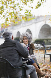 Lächelndes aktives Seniorenpaar genießt Kaffee im Herbstparkcafé - CAIF26455