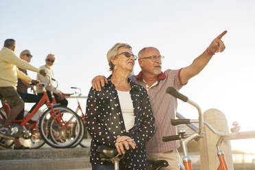 Aktives älteres Touristenpaar mit Fahrrädern und Blick auf die Landschaft - CAIF26465