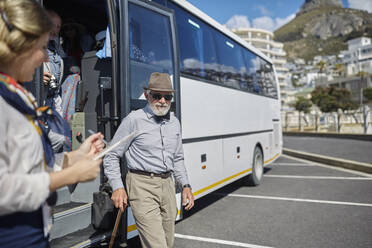 A senior blind man with white cane getting on public transport in city.  stock photo