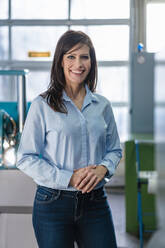 Porträt einer lächelnden Geschäftsfrau in einer Fabrik - DIGF10130