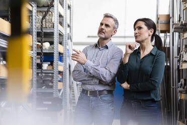 Businessman and businesswoman having a work meeting in storehouse of a factory - DIGF10139