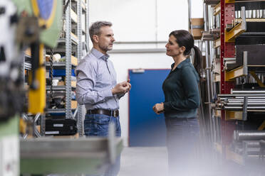 Businessman and businesswoman having a work meeting in storehouse of a factory - DIGF10142