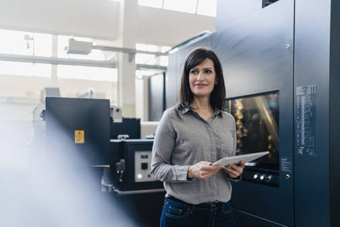 Confident businesswoman holding a tablet in a factory - DIGF10208