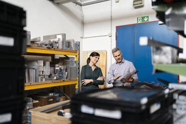 Businessman and businesswoman having a work meeting at a machine in a factory - DIGF10238