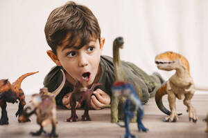 Porträt eines kleinen Jungen, der mit Spielzeugdinosauriern spielt - JRFF04417