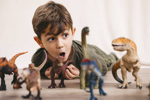 Portrait of little boy playing with toy dinosaurs - JRFF04417