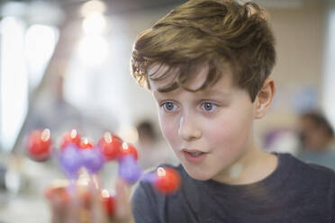 Neugieriger Junge, der ein Molekülmodell im Klassenzimmer untersucht - CAIF26510
