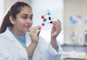 Curious girl student examining molecular structure in laboratory classroom - CAIF26515
