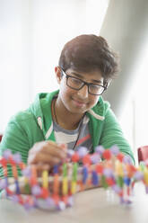 Smiling boy student assembling DNA model in classroom - CAIF26522