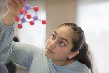 Curious girl student examining molecular structure in classroom - CAIF26532