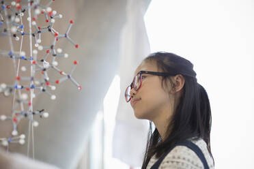 Nachdenkliche, neugierige Schülerin, die die Molekularstruktur untersucht - CAIF26541