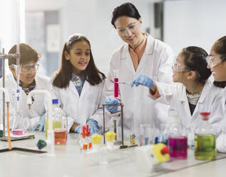 Female teacher and students conducting scientific experiment in laboratory classroom - CAIF26542