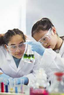 Studentin, die eine Flüssigkeit in einem Becherglas untersucht und ein wissenschaftliches Experiment in einem Laboratorium durchführt - CAIF26547
