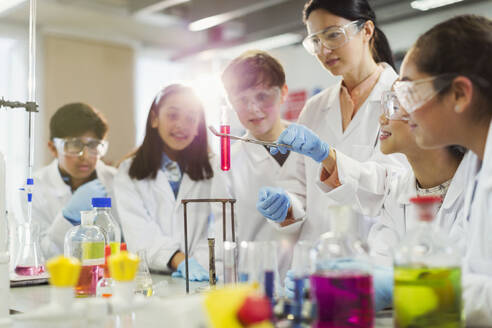 Lehrerin und Schüler führen ein wissenschaftliches Experiment durch und beobachten die Flüssigkeit im Reagenzglas in einem Klassenzimmer - CAIF26550