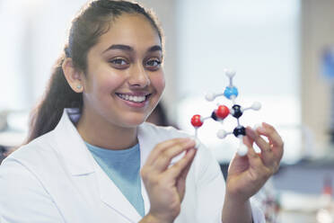 Portrait smiling girl student holding molecular model in laboratory classroom - CAIF26559