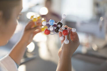 Neugierige Schülerin hält Molekülmodell im Klassenzimmer - CAIF26570