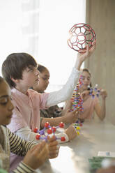 Focused boy student examining molecular structure in laboratory classroom - CAIF26577