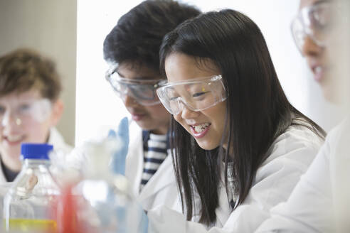 Lächelndes Mädchen bei der Durchführung eines wissenschaftlichen Experiments in einem Klassenzimmer - CAIF26579